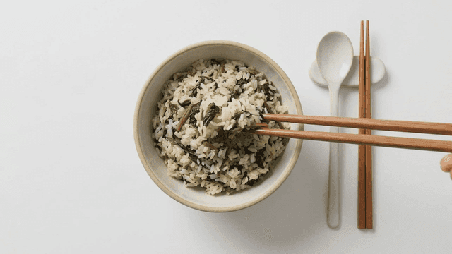 Warm bowl of vegetable rice picked up with chopsticks