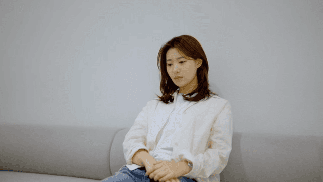 소파에 앉아 생각에 잠긴 여성