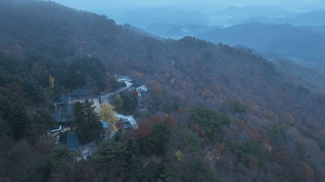 Misty mountain landscape with a distant hanok