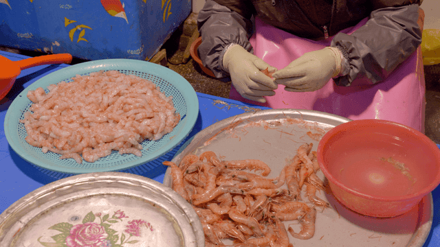 Person peeling shrimp by hand at seafood market