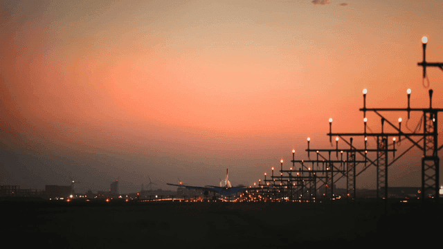 활주로 불빛과 함께 일몰에 착륙하는 비행기