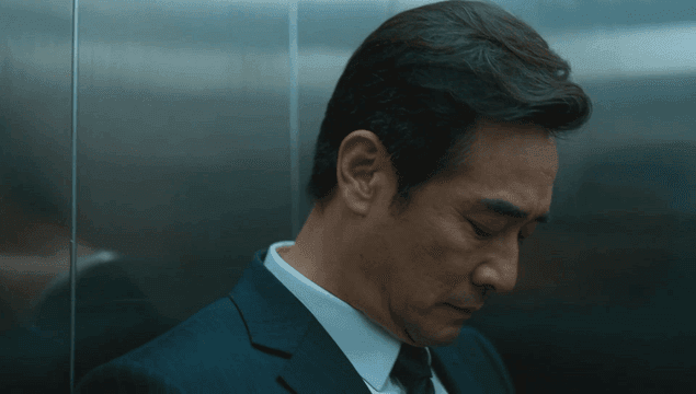 엘리베이터 벽에 기대어 있는 정장 입은 남자