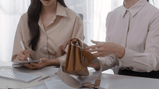 Two women discussing a handbag design