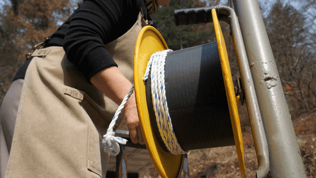 Person spinning large spool quickly outdoors