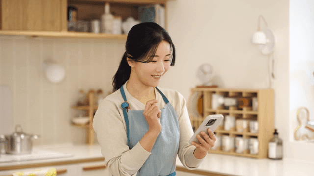 Woman in a kitchen using a smartphone