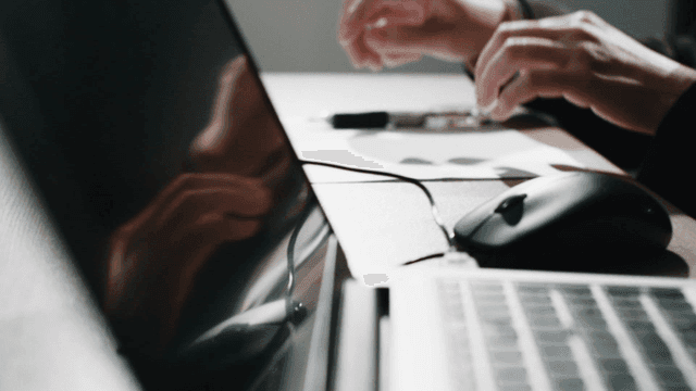 Hands typing and writing at a desk