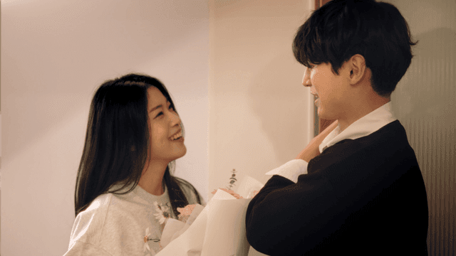 현관 문 앞에서 꽃을 주고받는 신혼부부