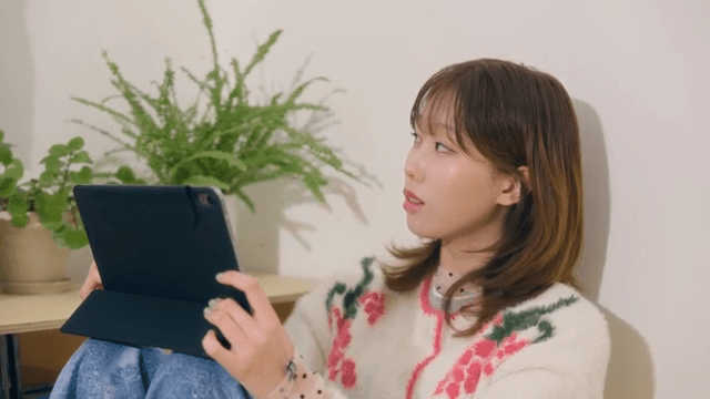 아늑한 방에서 태블릿을 사용하며 창문을 바라보는 여성
