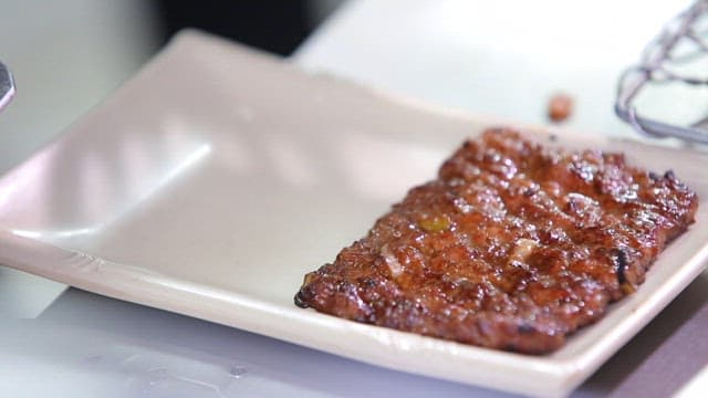 Grilled tteokgalbi being placed on a plate