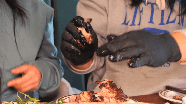 People wearing gloves deboning barbecue beef ribs