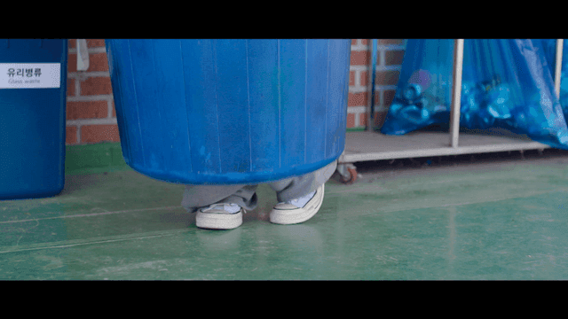Person hiding inside a blue trash bin