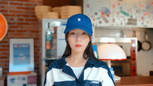 Woman wearing an expressionless blue hat in a pizza shop