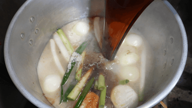 Soy sauce being poured into a boiling pot