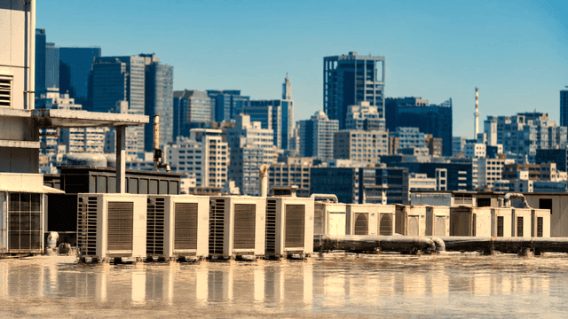 Rooftop view with air conditioner outdoor units against city skyline.