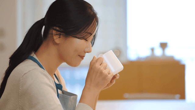 Woman enjoying cup of hot coffee indoors.