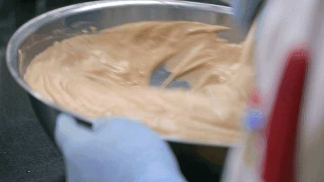 Baker mixing chocolate batter in large bowl.