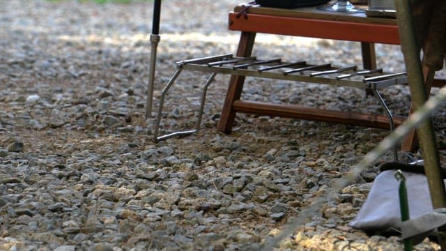 Setting up a portable grill outdoors on a gravel surface