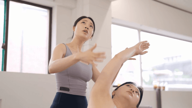 Pilates instructor guiding a student indoors