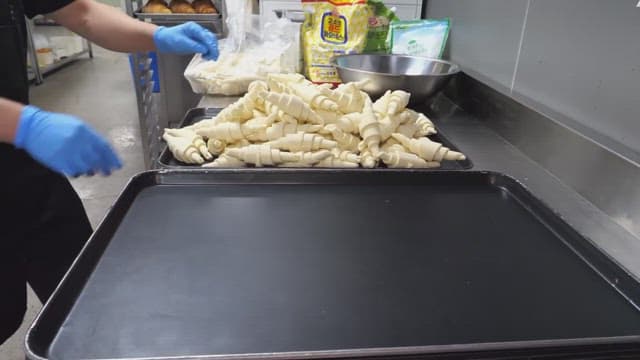 Placing croissant dough on a baking tray in an industrial kitchen