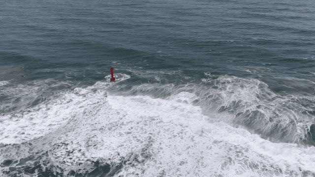 Waves crashing against a red lighthouse