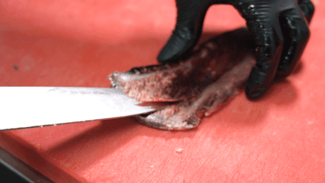 Cutting aged meat on red cutting board