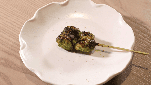 Grilled chicken breast skewers mixed with basil pesto on white plate