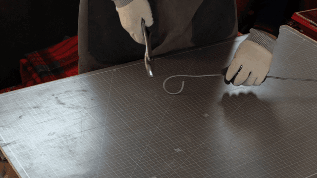 테이블 위에서 펜치로 철사를 구부리는 손