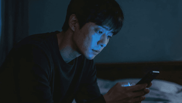 어두운 방에서 스마트폰을 사용하는 남자