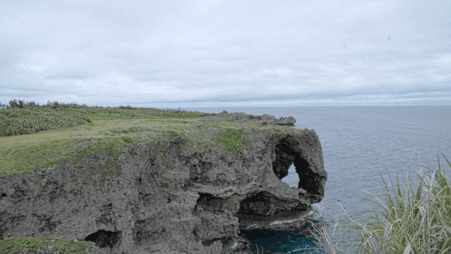 Rocky cliff by the ocean under a cloudy sky