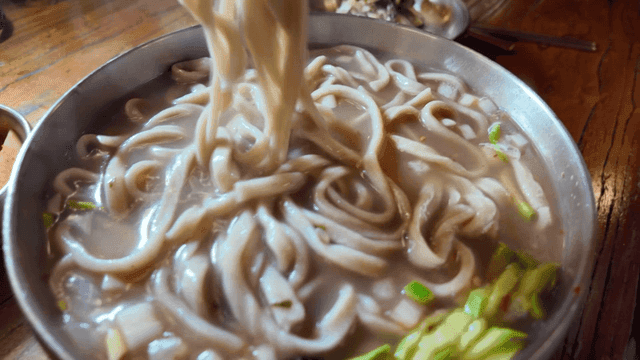 Chopsticks lifting kalguksu in savory broth