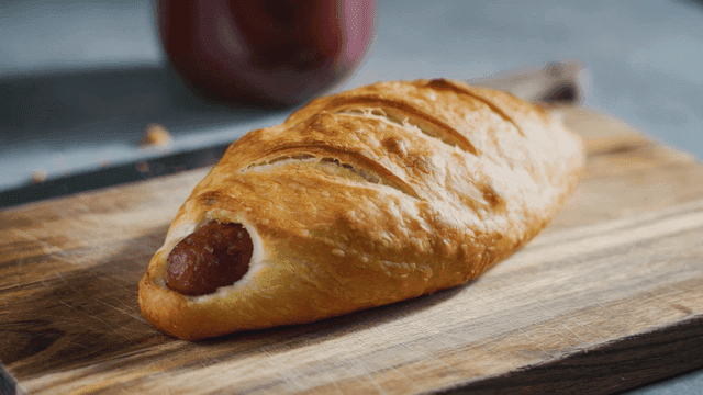 Freshly baked sausage roll on a wooden board