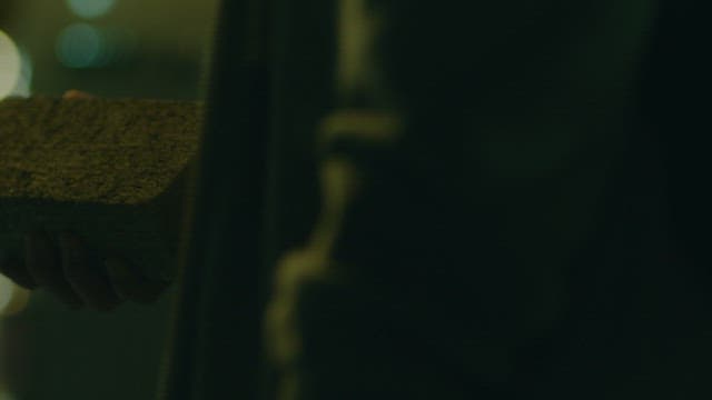 밤거리에서 손에 벽돌을 쥐고 있는 의문의 사람