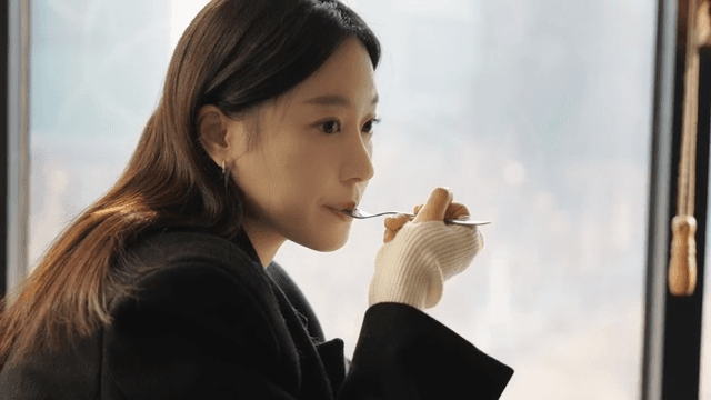 Profile view of a woman eating cake with a fork by a cafe window
