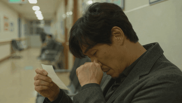 병원 복도에서 종이를 보는 남자