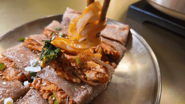 Chopsticks for placing bibim kalguksu on buckwheat pancake filled with kimchi