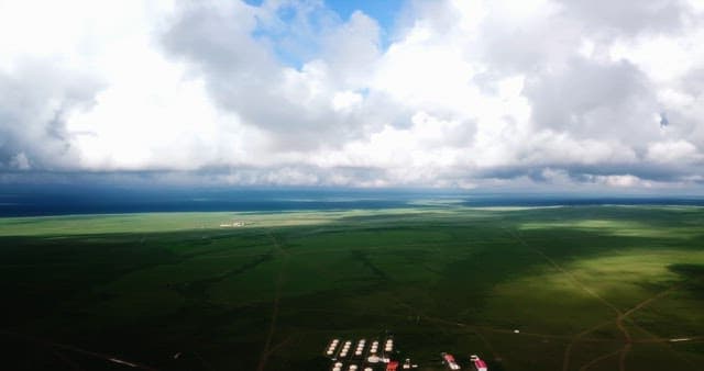 Vast green plains under a cloudy sky