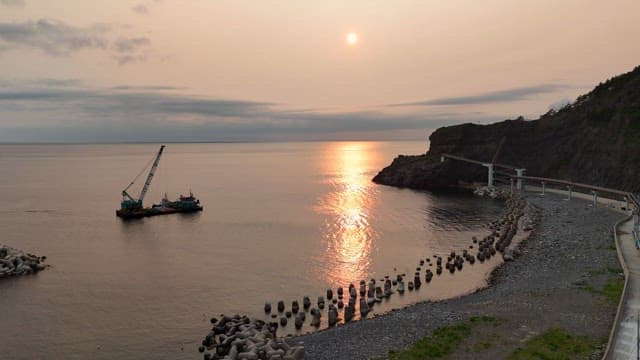 Sunset over a calm sea with a crane barge