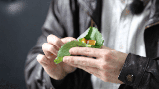 Hand wrapping meat in perilla leaf