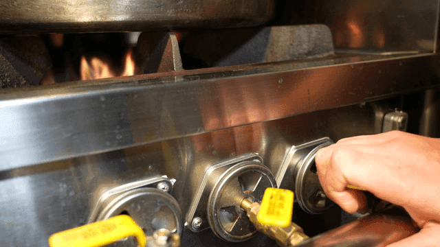 Adjusting the gas stove flame in a kitchen