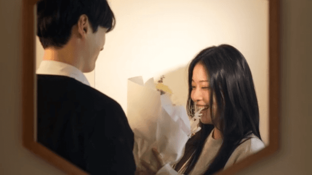 거울 앞에서 꽃을 주고받으며 즐거워하는 커플