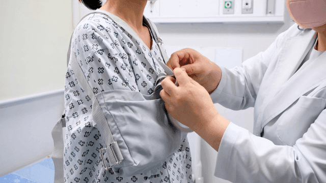 A doctor adjusting a patient's arm sling