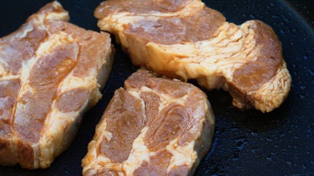 Grilling of juicy marinated pork on a hot frying pan