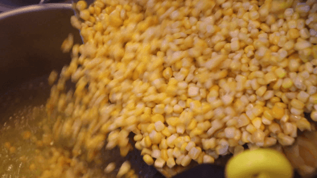 끓는 냄비에 옥수수를 붓는 장면