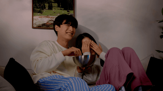 Couple watching scary movie on dark living room sofa