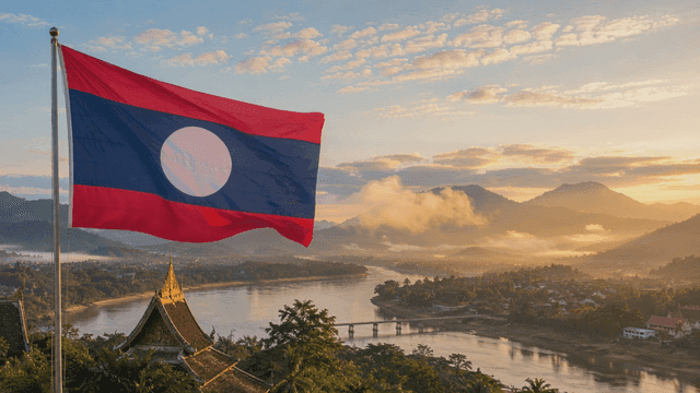 Laotian flag fluttering against backdrop of rivers and mountains.