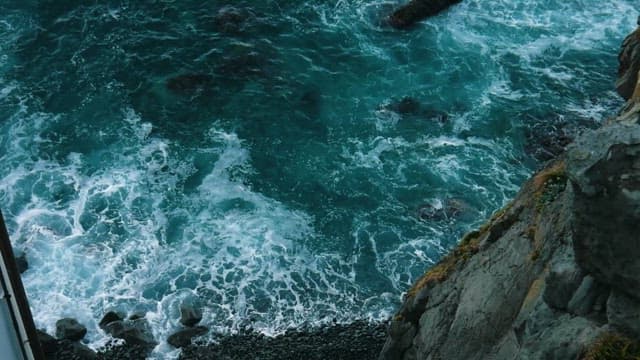 Aerial View of Turbulent Waves Against Rocky Cliffs