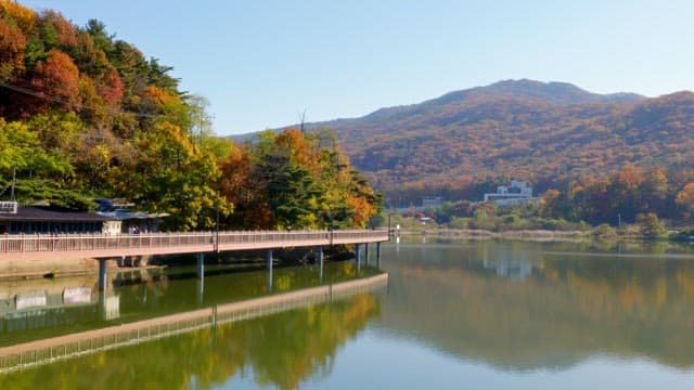 Baegunhosu Lake with a view of mountains and trees colored in autumn leaves and walking paths