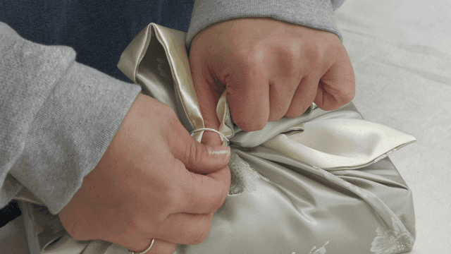 Hands delicately wrapping gifts with traditional fabric