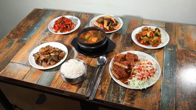 Table with various types of kimchi, rice, and kimchi stew