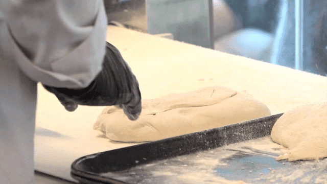 밀가루 위에서 반죽을 치대는 제빵사